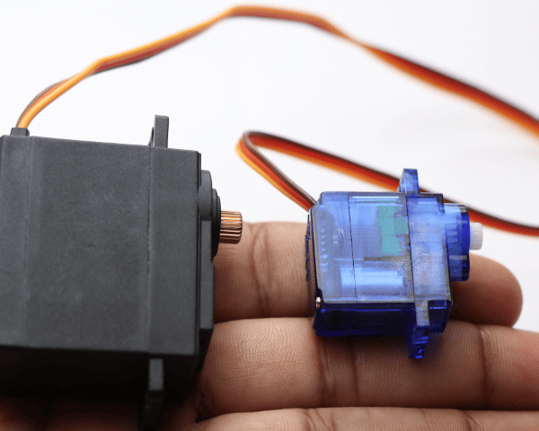 A person holding two different types of servo motors.