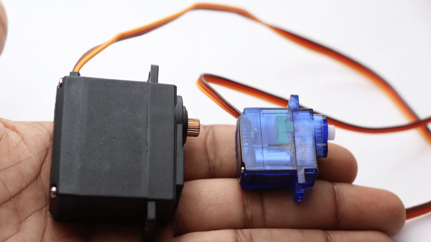 A person holding two different types of servo motors.