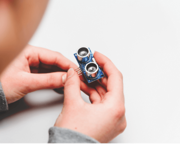 Hands holding an ultrasonic sensor module.