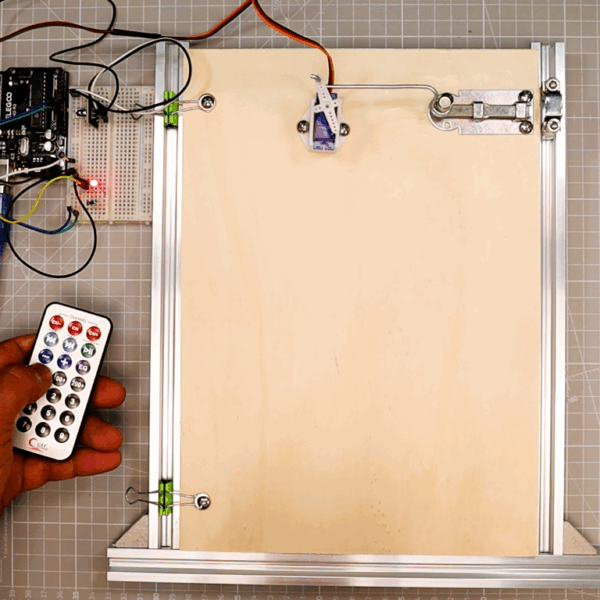 Arduino IR remote LED & servo door demo: Uno + KY-022, LED on breadboard, SG90 opening latch, kit remote in hand.