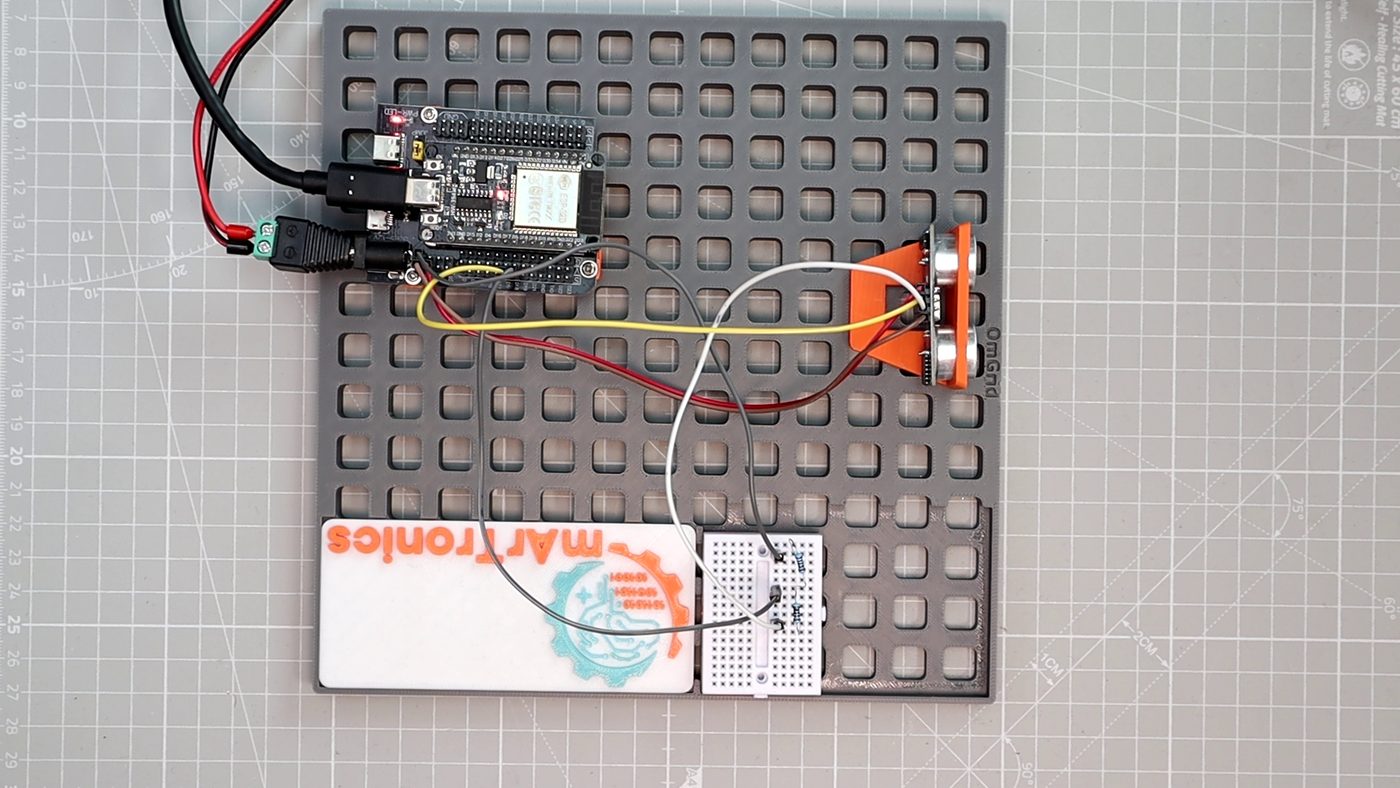 The printed OmBlock holding the HC-SR04 on the OmGrid, next to the ESP32 and the divider breadboard