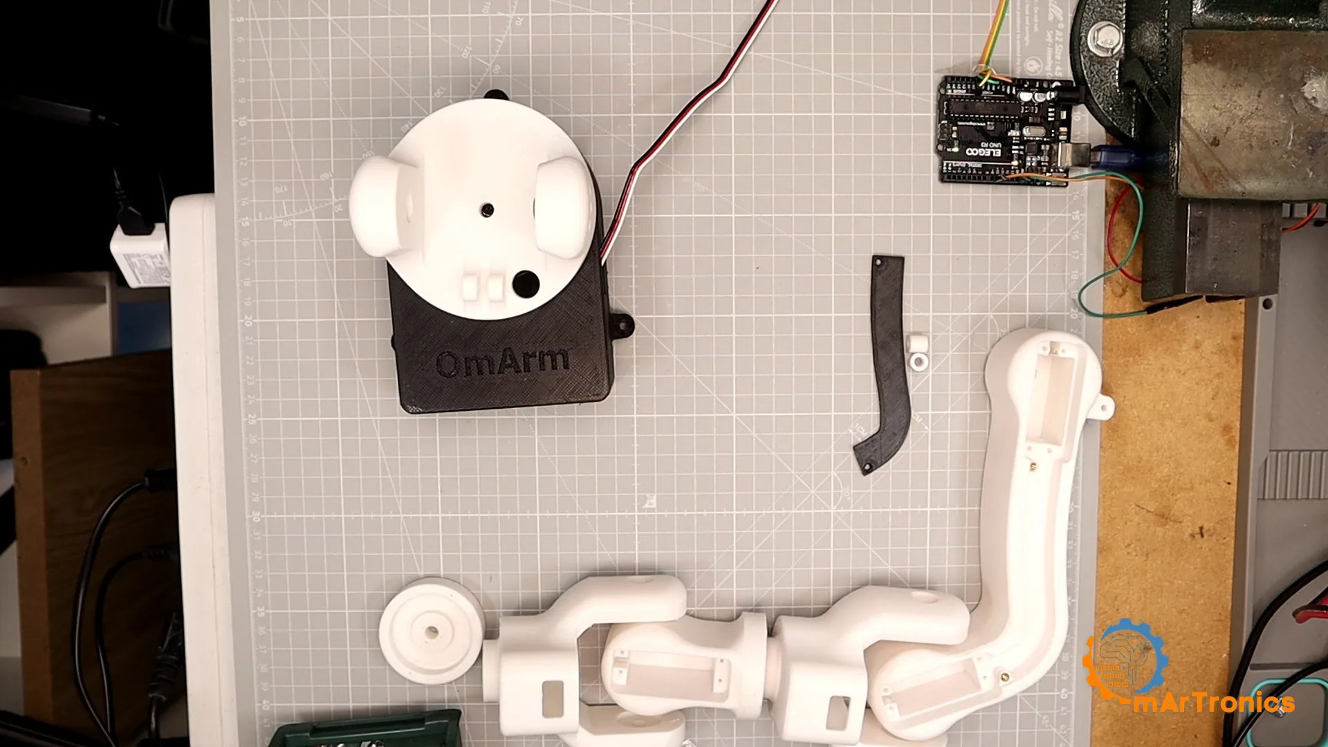 The printed parts of the arm laid out on a cutting mat during the build