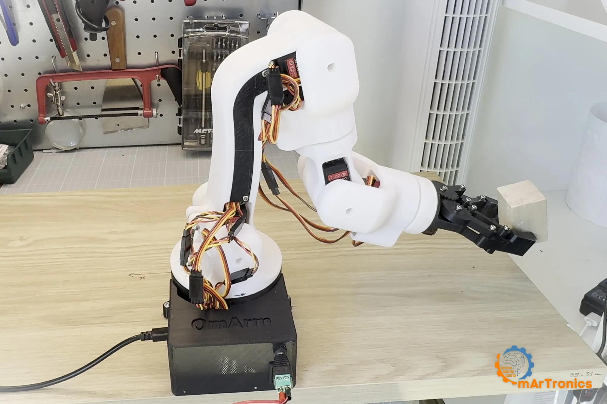 The assembled arm reaching out over the bench with the wooden block in its jaws